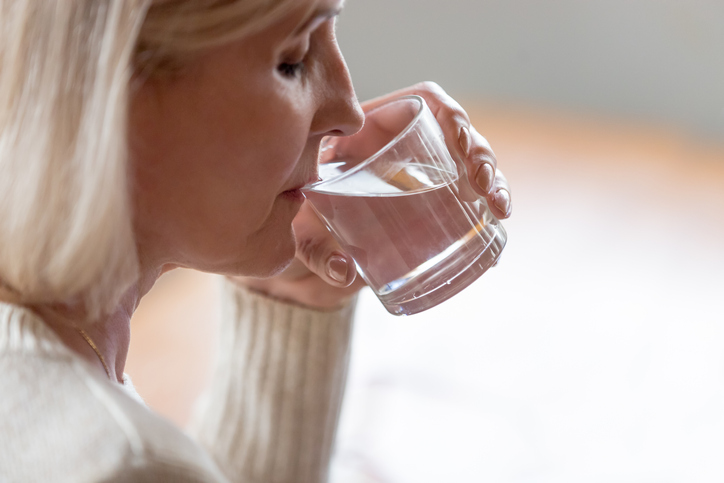 Persona mayor bebiendo agua para combatir la xerostomía